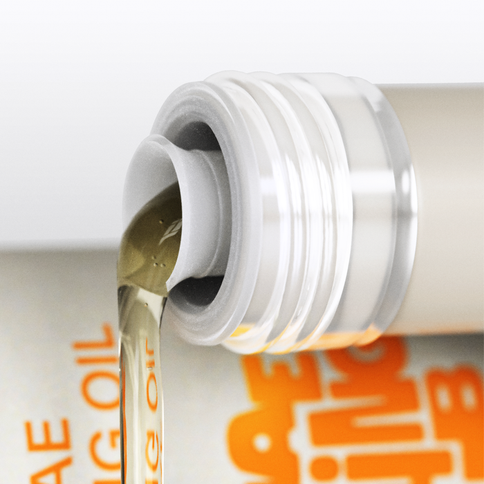 Close-up of Algae Cooking Club’s All Purpose Oil, a golden-colored, neutral tasting oil being poured from a bottle with a silver cap. The partially visible label in the background features bold orange text.