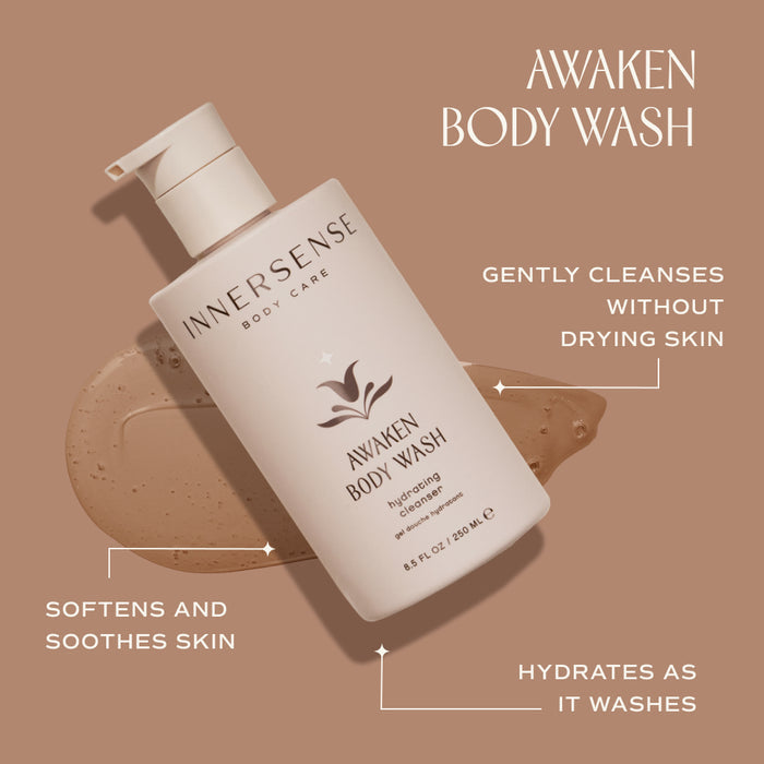 Bottle of Innersense Awaken Body Wash on a beige background, with product features labeled: "Gently cleanses without drying skin," "Hydrates as it washes," and "Softens and soothes skin." Brown liquid smear next to bottle.