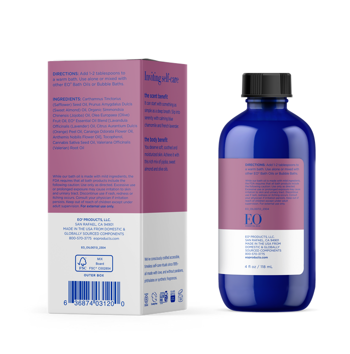 A blue EO Bath Oil bottle sits beside its box, which has a purple label with white and pink text. The box details ingredients and usage instructions, emphasizing soothing lavender for the body and scent. Ideal for an aromatherapeutic bath experience.