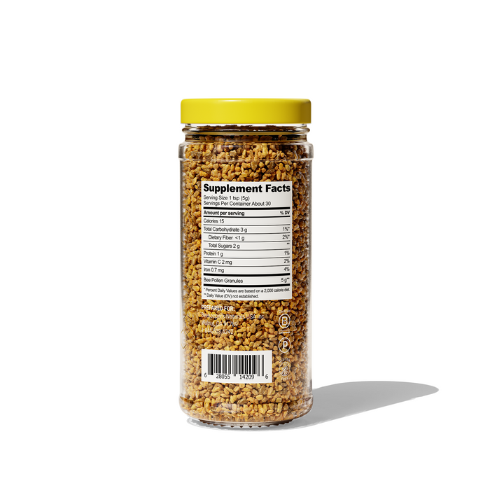 A clear plastic jar with a yellow lid contains small golden granules of Beekeepers Naturals Bee Pollen. The back label shows supplement facts and a barcode. Rich in antioxidants, the jar casts a shadow on the white background.