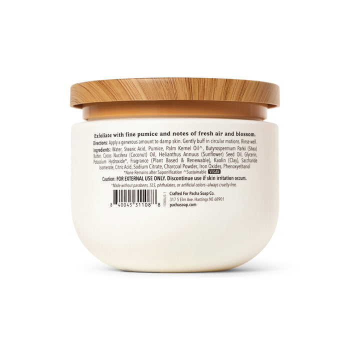 A white jar of Pacha Soap Co. Body Scrub with a wooden lid shows product info, directions, ingredients, cautions, and a barcode on the back label. Its gentle scrub formula helps keep skin hydrated.