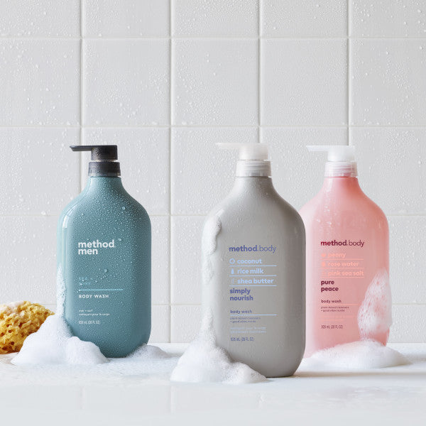 Three bottles of method Body Wash, free from parabens and phthalates, rest on a wet white surface. Each bottle is a different color: blue, gray, and pink. Surrounded by soap bubbles with a yellow sponge to the left, theyre ideal for those looking for mens body wash options too!.