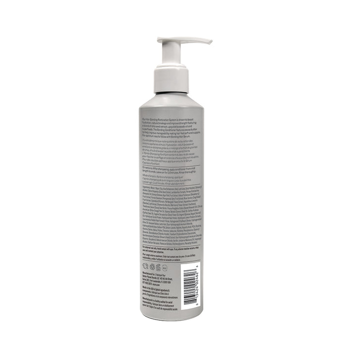 A tall, cylindrical gray bottle of Acure Bonding Conditioner with a white pump and detailed label stands upright against a plain white background. Infused with cocoa butter, it promises soft, supple hair.