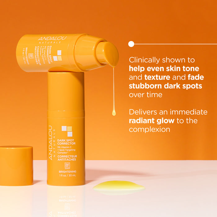 Two orange bottles of Andalou Naturals Dark Spot Corrector with droplet. Text highlights benefits: evens skin tone and texture, fades dark spots, and provides a radiant glow. Orange background.