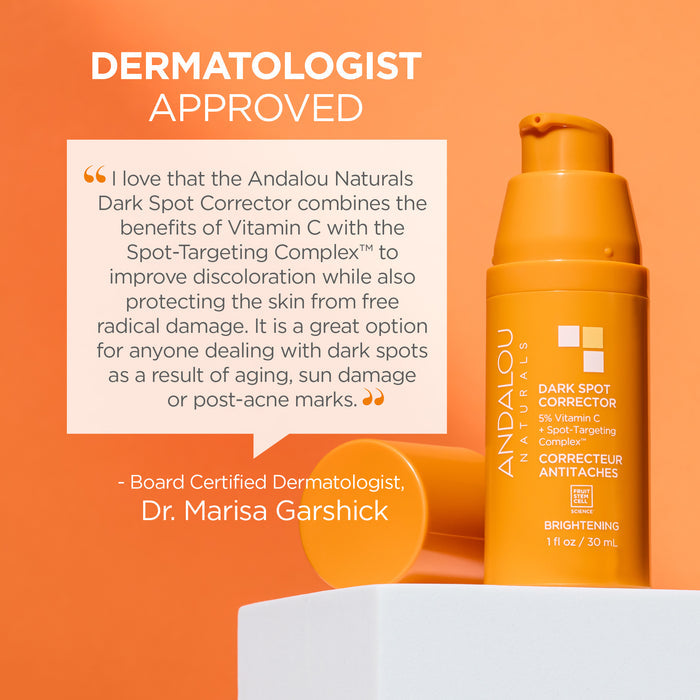 Orange bottle of Andalou Naturals Dark Spot Corrector against a light orange background. Text endorses the product's benefits for discoloration and protection by Dr. Marisa Garshick, emphasizing Vitamin C and spot-targeting complex.