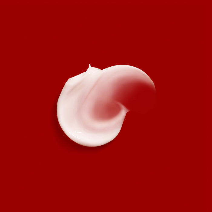 A swirl of Codeage Brightening Face Cream· Refill, enriched with glutathione, is spread on a solid red background, creating a soft, smooth texture that fades into a gentle gradient at the edges.