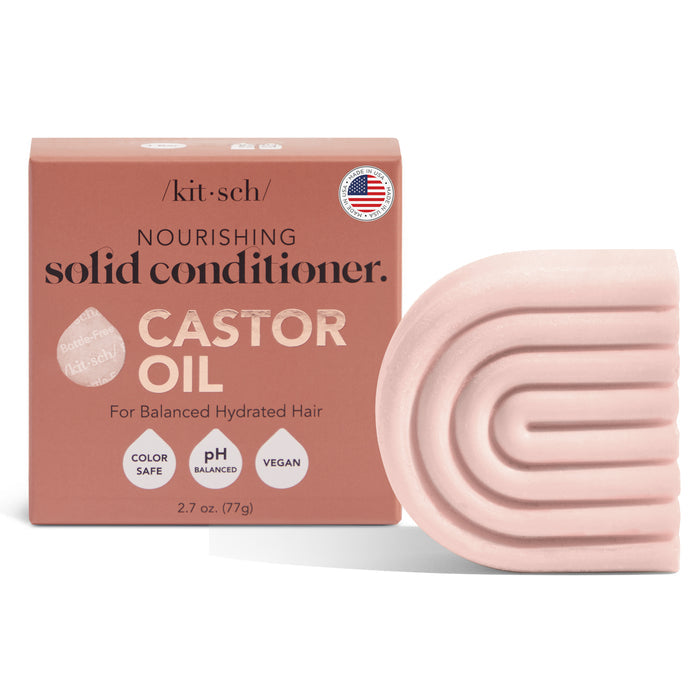 The image features a pink, arch-shaped Castor Oil Nourishing Conditioner Bar by Kitsch beside its packaging. The text reads: nourishing solid conditioner with castor oil, ideal for dry hair and frizz control, color safe, pH balanced, vegan, and made in the USA.