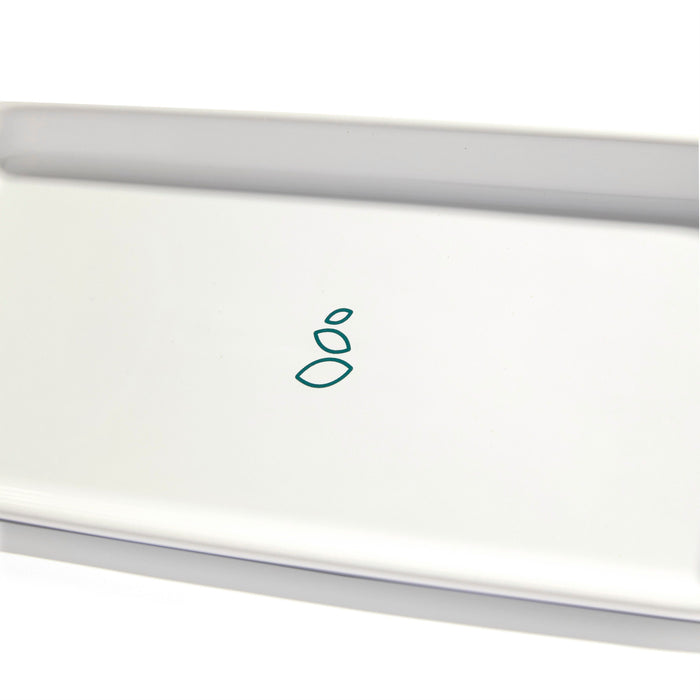 The Ceramic Sink-Side Tray by Grove Co. is a minimalist white rectangular tray featuring a simple green geometric pattern with three overlapping shapes at its center, adding modern sophistication to any bathroom or kitchen setting.