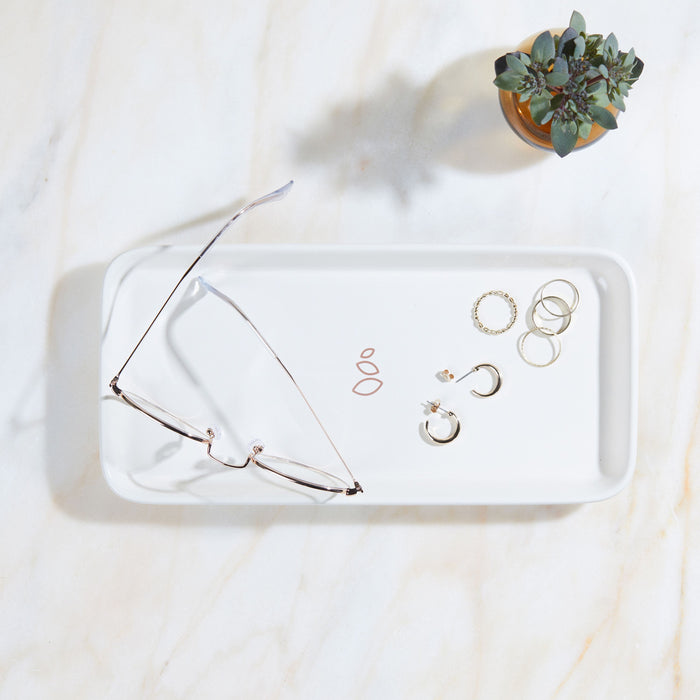 A Grove Co. Ceramic Sink-Side Tray on marble holds eyeglasses, hoop and stud earrings, and rings, with a small potted succulent nearby.