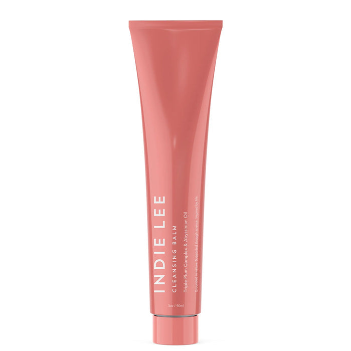 An upright pink tube of Indie Lee Cleansing Balm with white text on a white background—a clean skincare cleanser with vitamin C for radiant skin.