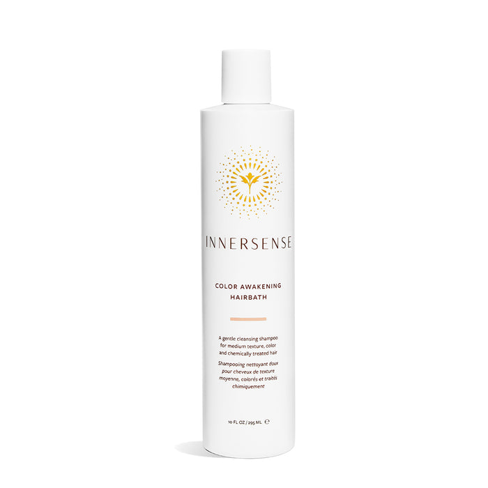 The Innersense Organic Beauty Color Awakening Hairbath shampoo, ideal for color-treated hair, comes in a white cylindrical bottle with a golden logo and flat cap, set against a plain white background, promising vibrant hair with every wash.