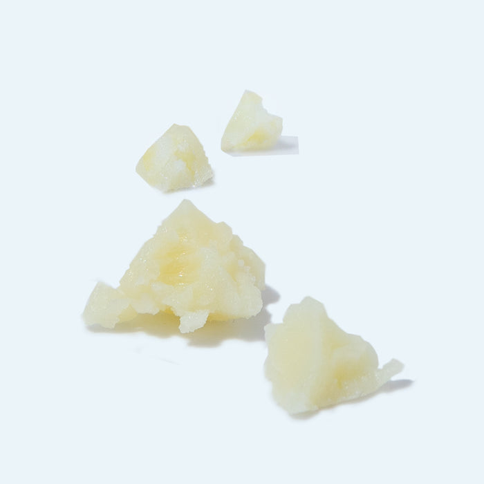 Scattered across a light background are small chunks of soft, pale yellow wax in varied sizes. Their crumbly texture suggests they are ideal for crafting Pedestrian Projects Cracked Heel Repair solution.