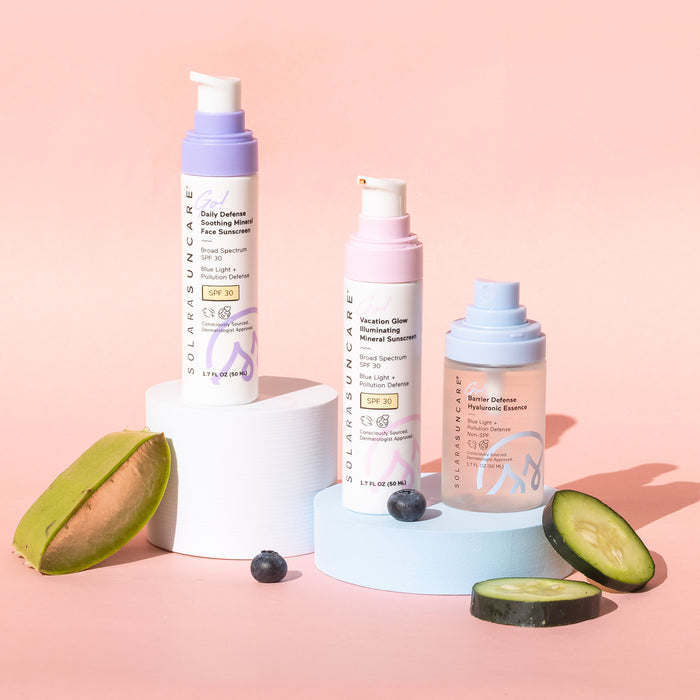 Three bottles of Solara Suncares Daily Defense Soothing Daily Moisturizer SPF 30 are displayed on white platforms with aloe vera, cucumber, and a blueberry. The pastel pumps suit sensitive skin and work as a daily face moisturizer.