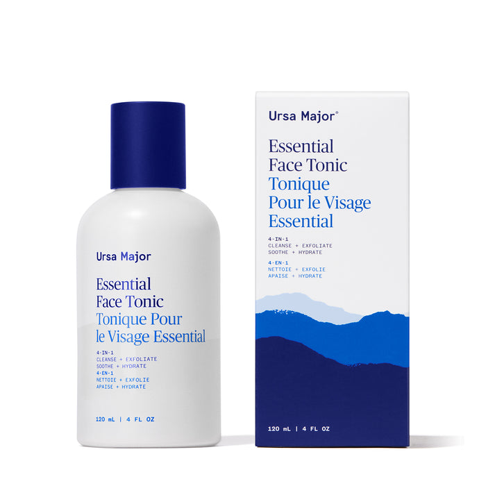 A white bottle and box of Ursa Major Essential Face Tonic (120 mL/4 fl oz), with blue text and minimalist mountain graphics. This exfoliating tonic, labeled in English and French, promotes clearer skin.