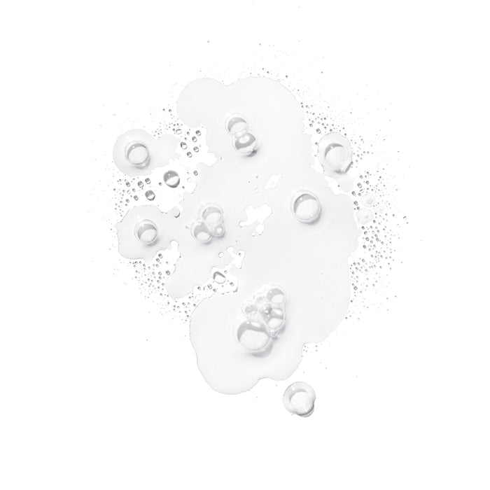Clear liquid droplets and bubbles on a white background evoke the refreshing splash of Ursa Major Essential Face Tonic, a gentle exfoliator for clearer skin.