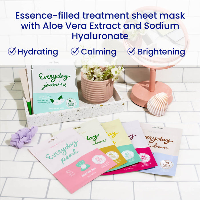 On a bathroom counter, five colorful Everyday 8 sheet masks by FaceTory highlight their plant-based, hydrating, calming, and brightening properties. A small pink fan sits nearby alongside a potted plant and folded towels.