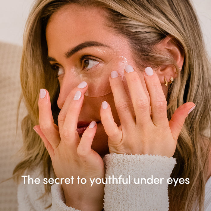 A woman applies Uncommon Beauty Eye Masks under her eyes, gently pressing them into place. Text on the image reads, The secret to a youthful glow.