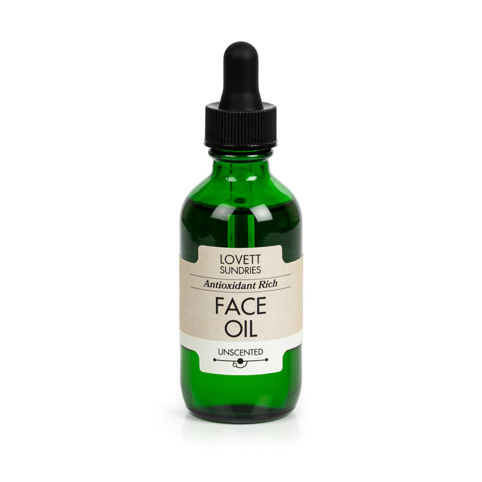 Lovett Sundries Face Oil comes in a green glass bottle with a black dropper. The label, featuring a minimal vintage design, describes an unscented blend of antioxidant-rich organic oils that promote skin elasticity.