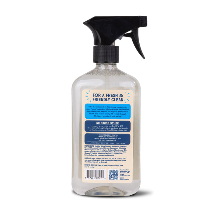 The image shows Aunt Fannies Glass & Window Cleaner in a spray bottle with a black nozzle. The label, in blue and beige, highlights its plant-based, vinegar-infused formula free of harmful substances. Additional details and instructions are beneath the main text.