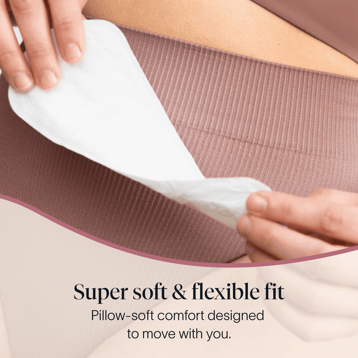 A person places a Cora Got-You-Covered Pantyliner – Light Absorbency onto mauve ribbed underwear. Text reads: “Super soft & flexible fit. Pillow-soft comfort designed to move with you.”.