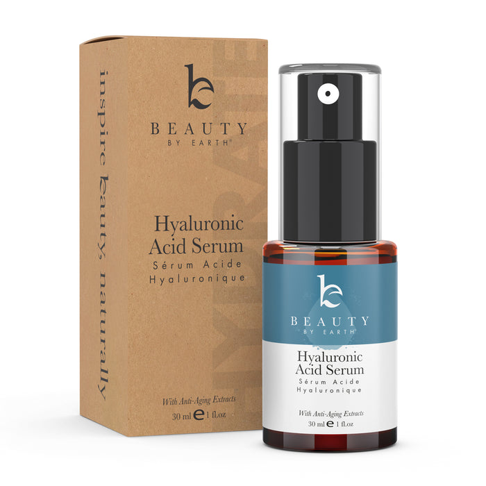 A brown cardboard box and a Beauty by Earth Hyaluronic Acid Serum bottle with a black pump are displayed. The label reads With Anti-Aging Extracts, 30 ml / 1 fl oz, promising hydration and a youthful glow.
