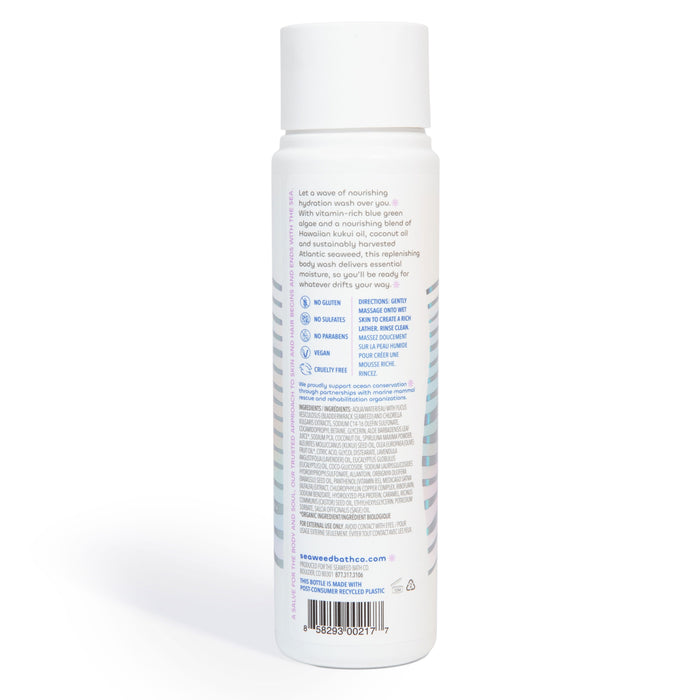 The back view of a white Hydrating Body Wash bottle by The Seaweed Bath Co shows text and icons for sensitive skin care benefits. It lists directions, bladderwrack seaweed ingredients, and eco-friendly credentials. The bottle features a white cap against a plain background.