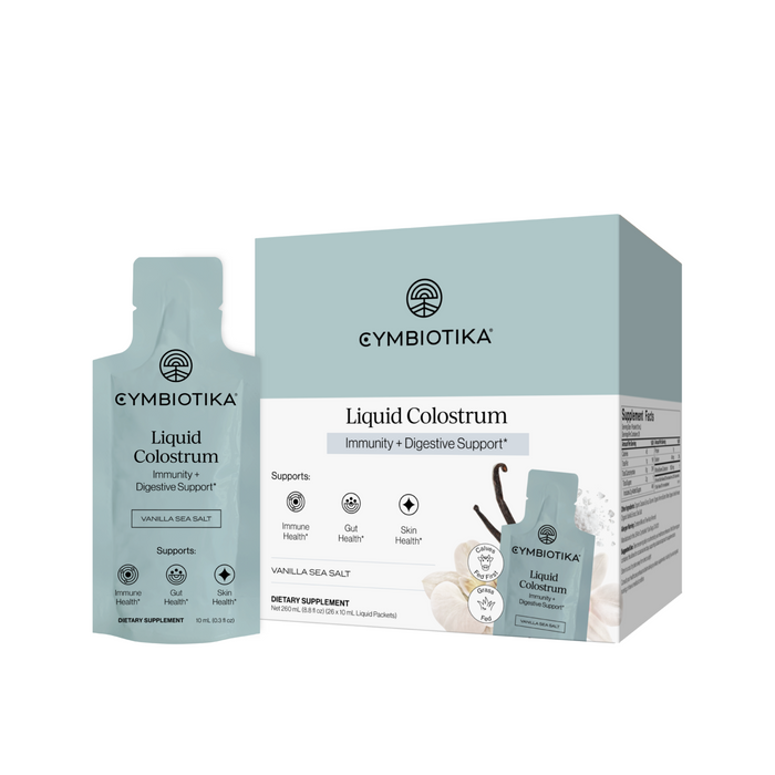 Cymbiotika Liquid Colostrum, labeled for immune support and digestive health, features vanilla and coconut imagery on its packaging and highlights benefits for immunity, skin, and gut health. Available in box and single packet formats.
