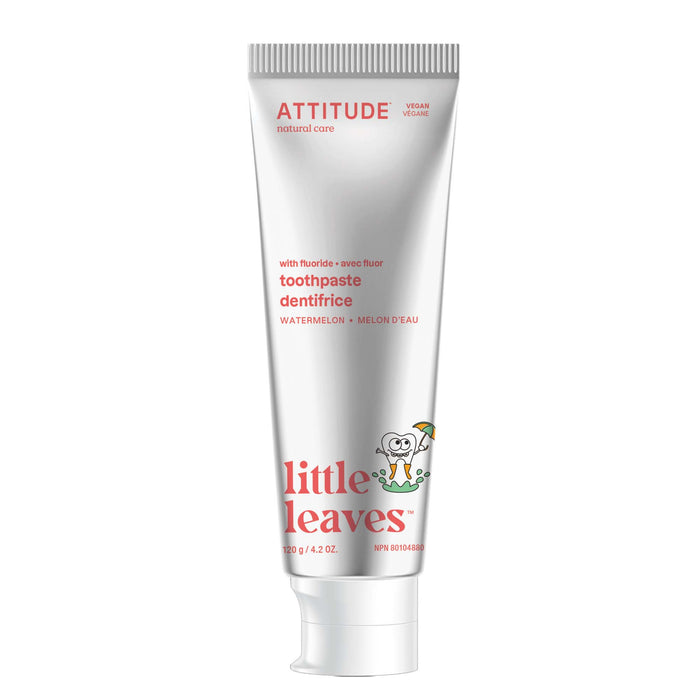 A mostly white tube of ATTITUDE little leaves Toothpaste with Fluoride, watermelon flavor, features red and green text and a cartoon tooth holding an umbrella on the front.