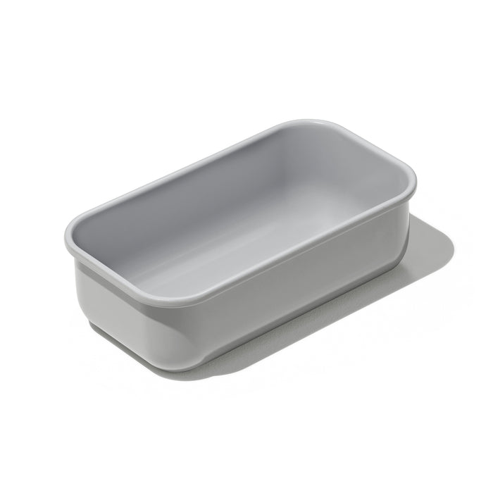 The Caraway Loaf Pan is rectangular and light gray with rounded edges, shown at a slight angle. It has a smooth matte finish and non-toxic ceramic coating, casting a subtle shadow on the white background.