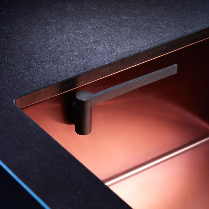 A modern copper sink with a black countertop boasts a sleek, minimalist black faucet. The HAPPY SiNKS Magnetic Dishcloth Holder, crafted from biocomposite material and featuring the Magnet Fitting System, enhances functionality without sacrificing the warm aesthetic.