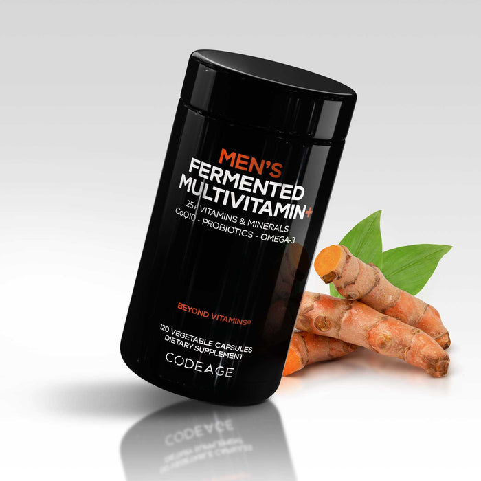 A black bottle of Codeage Mens Fermented Multivitamin+ sits beside turmeric roots and green leaves, highlighting 25+ essential vitamins and minerals, CoQ10, probiotics, and omega-3—all from whole food supplements.