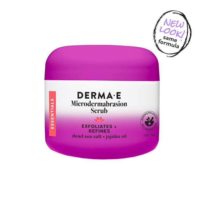 A purple and white jar of Derma E Microdermabrasion Scrub, an exfoliating facial scrub labeled “Exfoliates + Refines” with dead sea salt and jojoba oil. The packaging features a “New look! Same formula.” sticker and displays the Essentials label, highlighting its blend of microdermabrasion ingredients for smooth, radiant skin.