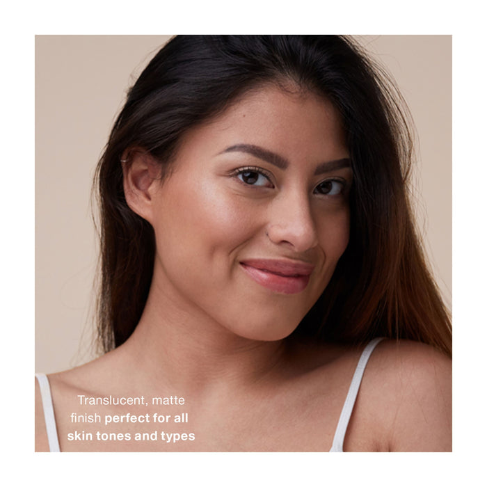 A woman with long dark hair and natural makeup smiles at the camera against a beige background. Text reads: Mineral Fusion Mineral SPF 30 Brush-On Sun Defense—translucent, matte finish powder for all skin tones and types.