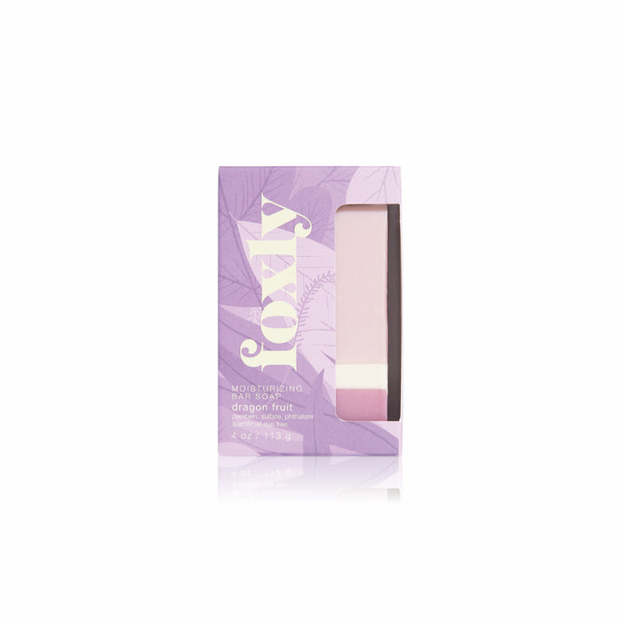 The Foxly Moisturizing Bar Soap is a pastel pink soap made with nourishing oils, packed in a lavender box with white "FOXY" and "dragon fruit" text, plus a clear window revealing the creamy lather inside.