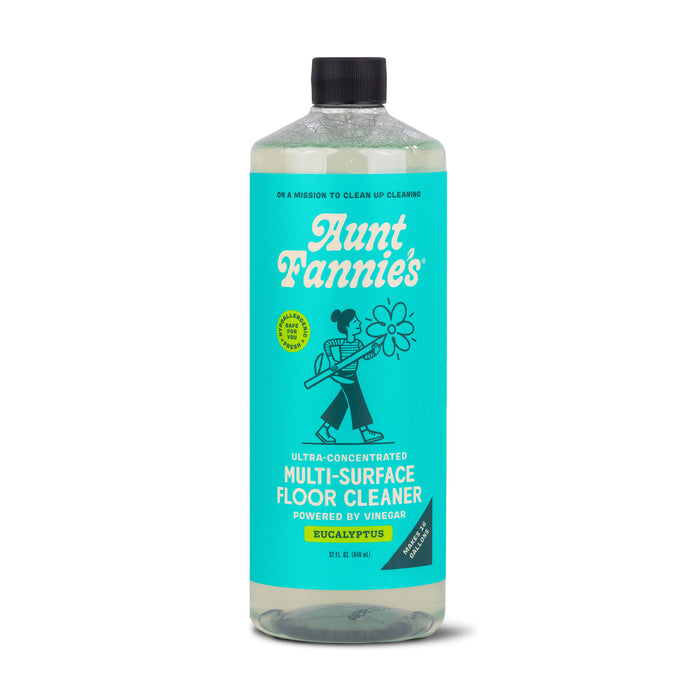 Aunt Fannies Multi-Surface Floor Cleaner in eucalyptus scent contains plant-based surfactants with a vinegar base. The 32 fl oz (946 ml) turquoise bottle has a white-text label showing a person mopping, perfect for all surfaces.