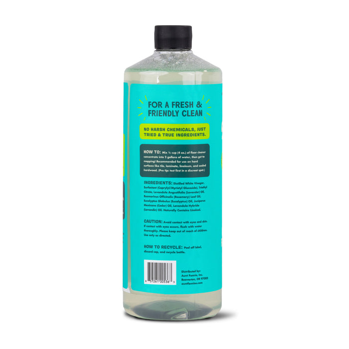A tall Aunt Fannies Multi-Surface Floor Cleaner bottle has a blue label with white and yellow text for instructions and ingredients. It has a transparent cap, contains light green plant-based surfactants, and highlights eco-friendliness and recycling.