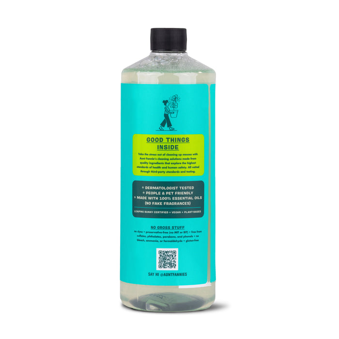 A tall, clear bottle with a turquoise label and black cap from Aunt Fannies highlights its vinegar-powered formula. The Multi-Surface Floor Cleaner emphasizes benefits of essential oils and plant-based surfactants, ensuring no fake fragrances, with an illustration of someone watering a plant.