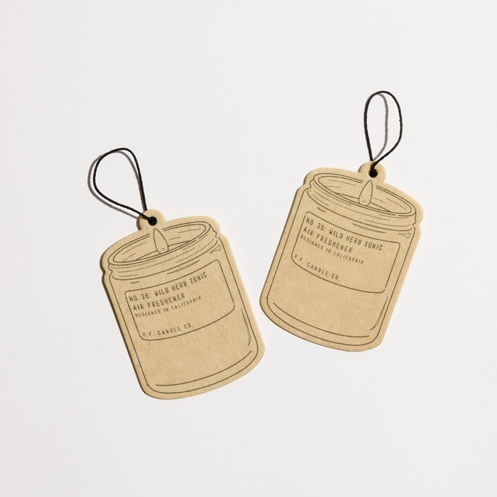 Two brown, jar-shaped air fresheners with black strings are shown against a white background. Each has a minimalist label: Mushroom Wellness Lions Mane Blend Caps by Herb Pharm, inspired by memory-boosting botanicals.