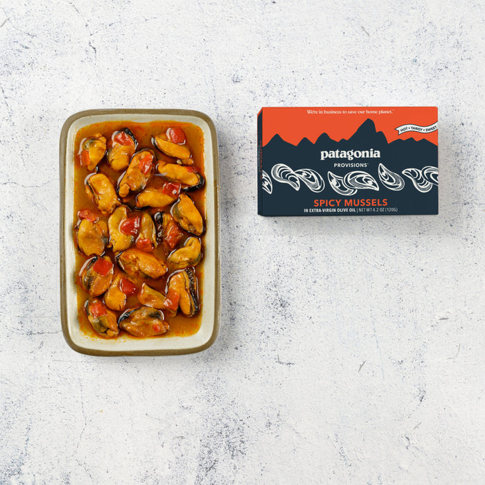 A rectangular dish of Mussels Spicy made with Extra Virgin Olive Oil sits beside a box labeled Patagonia Provisions on a light, textured surface.