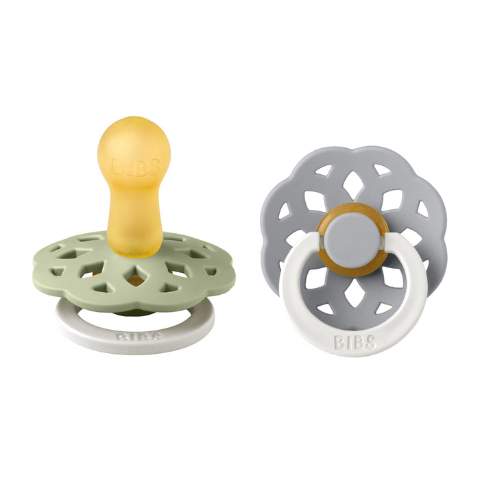 Two BIBS pacifiers are shown: one with a green shield and yellow nipple, the other gray with a white ring handle. Both have flower designs, breastfeeding support with natural rubber nipples, and glow in the dark.