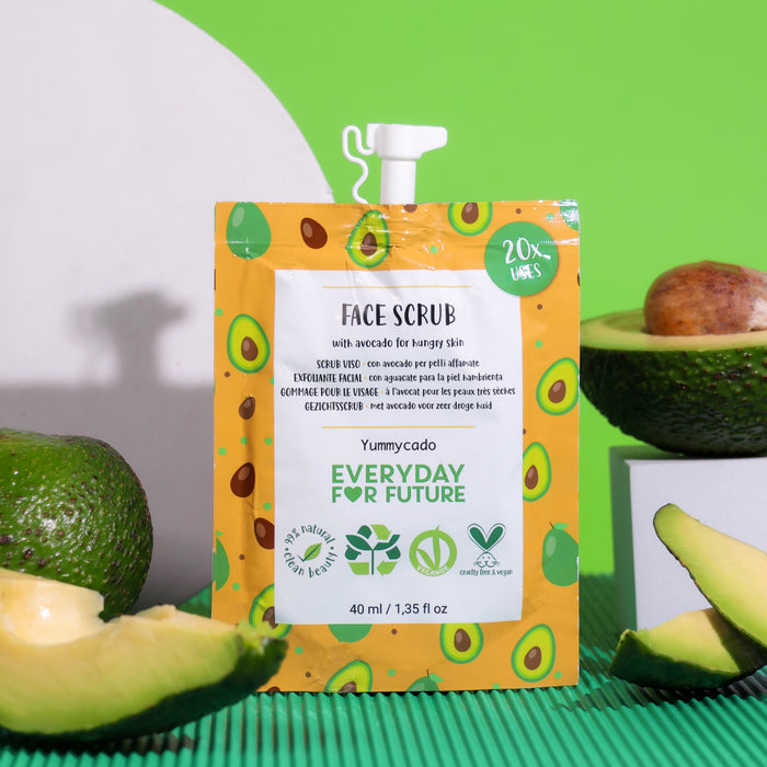 A package of Nourishing Avocado Face Scrub by Everyday For Future, featuring avocado illustrations and eco-friendly claims like zero waste and natural ingredients, is displayed among fresh avocado halves on a vibrant green and white background—perfect for your skincare routine.