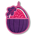 The Neighborgoods Pot Holder - Fig features a purple and pink cotton fig-shaped design with a decorative leaf, seed pattern, and hanging loop—this kitchen essential also works as a charming oven mitt.