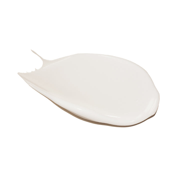 A smooth, white creamy substance resembling Innersense Organic Beautys Renew Body Lotion is spread thinly on a plain white background, forming an irregular oval shape with a small tail extending from one end.