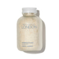 A frosted jar with a white cap and the Naturally London label holds Revitalizing Foot Soak—a pale, grainy powder in pomelo mint scent that soothes, exfoliates, and relieves dry, itchy skin.