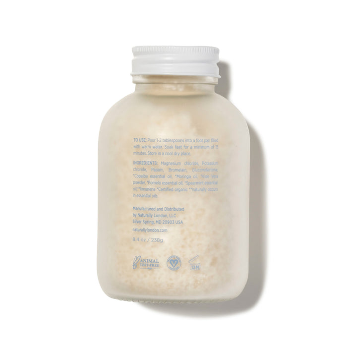 Naturally London’s Revitalizing Foot Soak comes in a clear, white-capped bottle filled with off-white crystals. The back label provides instructions, ingredients, and details in blue text to help soothe dry, itchy skin.