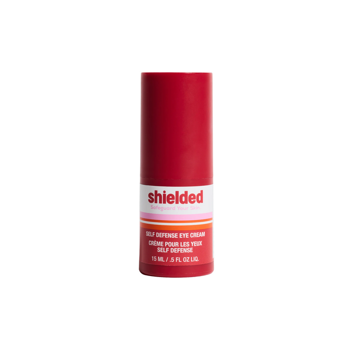A red and white bottle of Shielded Beauty Self Defense Eye Cream, 15 mL (0.5 fl oz), for dark circles and under-eye bags, features English and French on the label, shown against a white background.