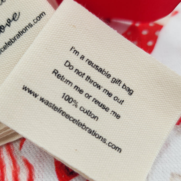 Close-up of a fabric label on a cream cloth from Waste Free Celebrations’ Sew Your Own Set of 10 gift bags - Candy Cane Baubles, reading: I’m a reusable gift bag. Do not throw me out. Return me or reuse me. 100% cotton.