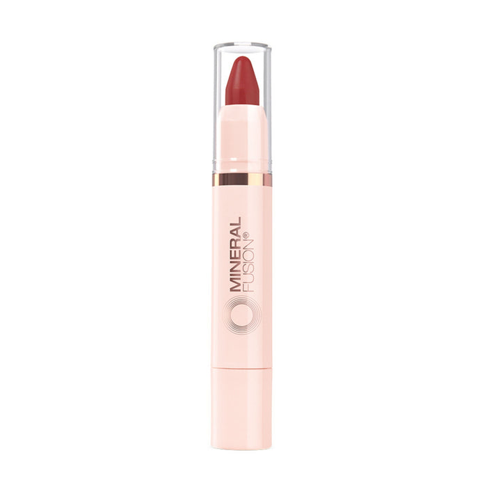 A Mineral Fusion Sheer Moisture Lip Tint with a pinkish-beige body, clear cap, and red tip stands upright against a white background.