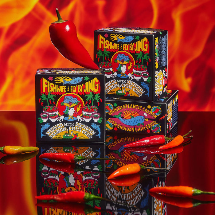 Stacks of Fishwifes Smoked Salmon with Sichuan Chili Crisp are surrounded by red chili peppers, set against a backdrop of fiery orange and red flames, crafting a spicy atmosphere ideal for Kvarøy Arctic delicacies.