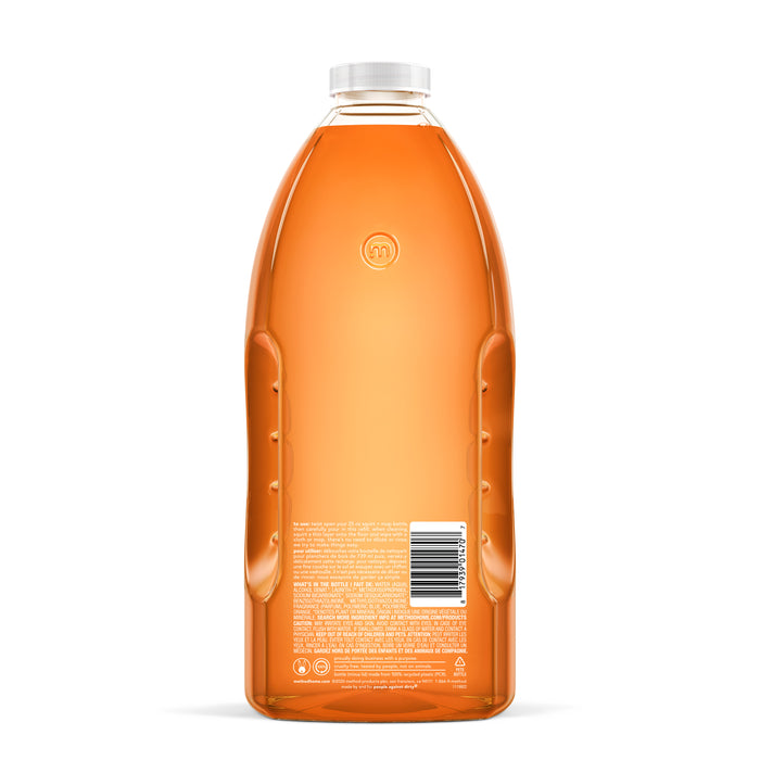The method Squirt Mop Wood Floor Cleaner Refill comes in a clear recycled plastic bottle with ergonomic side grips. It holds orange liquid, has a white cap, and includes a back label with small text and a barcode.